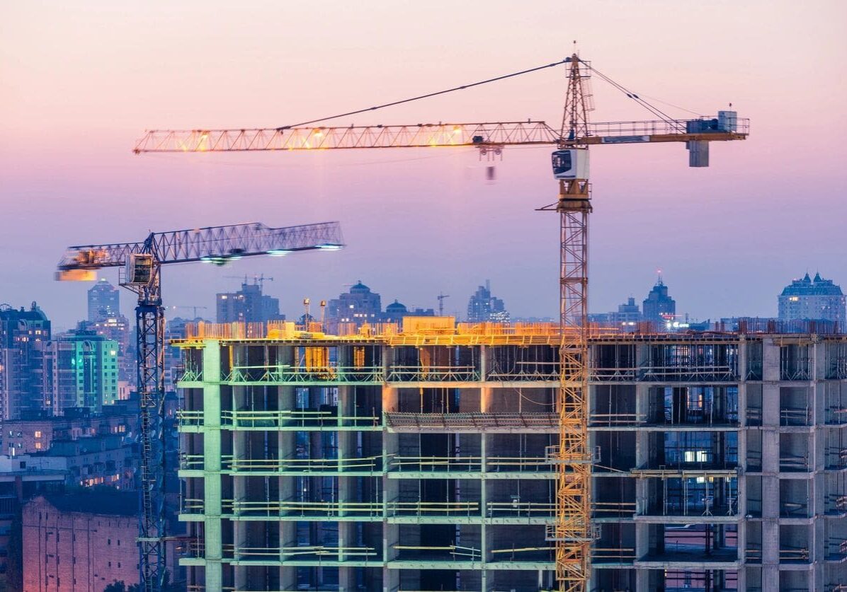 A building under construction with cranes in the background.